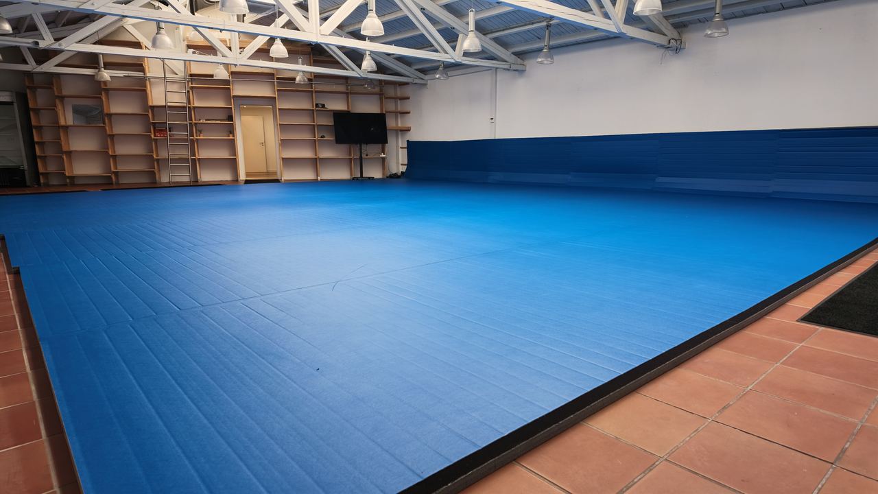 Die Trainingshalle von Imperial Ground: 120 m² blaue Dollamur-Tatami, Regale an der hinteren Wand